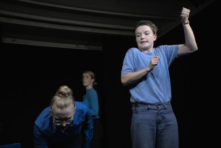 three people dressed in blue making odd movements