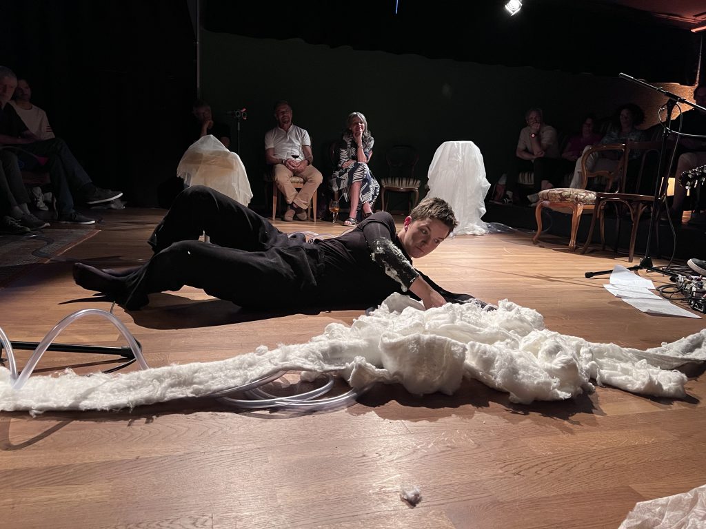 a performer lying on the floor animating a white fluffy material